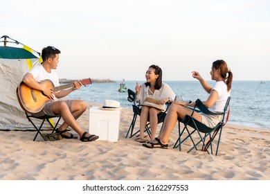 Happy friend have fun playing guitar and clap in camp they smiling together in holiday on sand beach near camping tent vacation time at sunset, Young Asian group woman and man in summer travel outdoor - Powered by Shutterstock