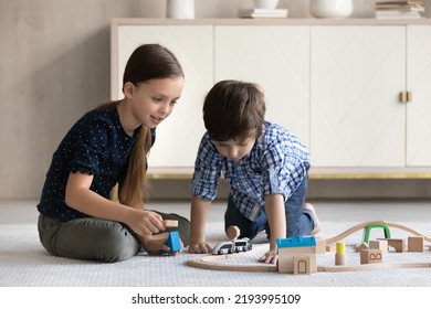 Happy Friendly Adorable Little Brother Sister Kids Sitting On Cozy Floor Carpet, Playing With Toy Railway Road, Enjoying Stress Free Leisure Weekend Playtime Together At Home, Daycare Concept.