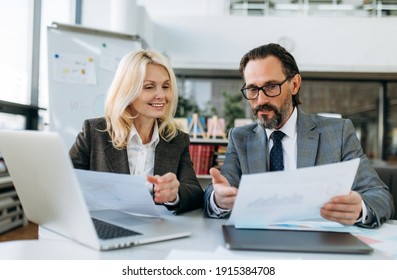 Happy friendly colleagues learning financial document for business plan. Successful influential mature coworkers working on corporate project,  discuss some ideas, partnership concept