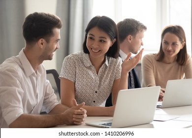 Happy Friendly Diverse Employees Talking Laughing Working Together Discussing Good News Joking Sitting With Coworkers Laptops, Smiling Office Workers Having Fun Sharing Ideas Chatting At Work Break