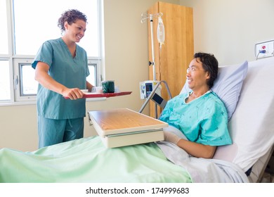 Happy friendly mid adult nurse bringing breakfast for mature patient in hospital - Powered by Shutterstock