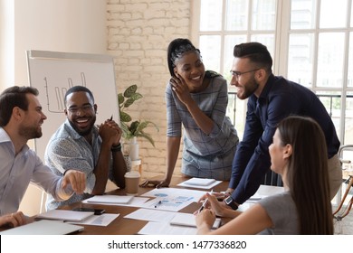 Happy friendly multiracial business team laughing working together at corporate briefing gathered at table  cheerful diverse office people group having fun talking enjoy teamwork during staff meeting