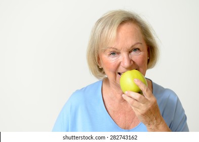 Happy friendly smiling senior lady with a fresh healthy ripe green apple in her hand in a healthy diet and nutrition concept