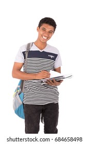 Happy Friendly Teenage Boy With Backbag Smiling And Holding A Notebook, Teenager Wearing Striped Gray T-shirt And Black Jeans,  Isolated On White Background