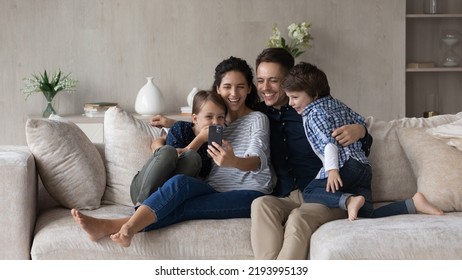 Happy friendly young couple family and small children siblings recording funny video on cellphone web camera, posing for selfie photo, watching content in social network, tech addiction concept. - Powered by Shutterstock