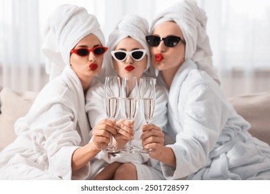 Happy friends in bathrobes with sunglasses and glasses of sparkling wine indoors, selective focus. Spa party - Powered by Shutterstock