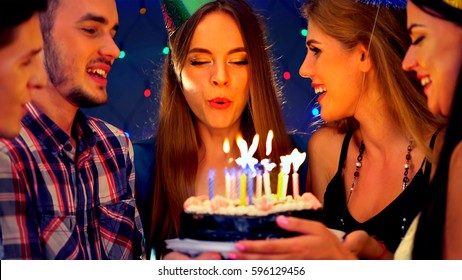 Happy friends birthday celebrating food with celebration cakes. Meet people wear in hat party blow out candles at burning candles. Two women and men have fun in nightclub.Youth celebrates together. - Powered by Shutterstock