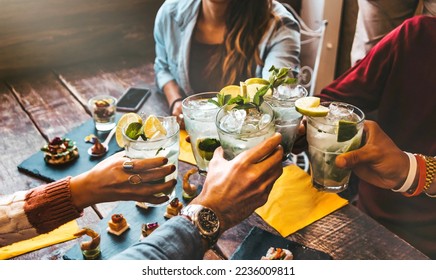 Happy friends celebrating party toasting mojito drinks at cocktail bar restaurant - Young people having fun drinking cocktails on happy hour at pub - Beverage and youth concept - Powered by Shutterstock