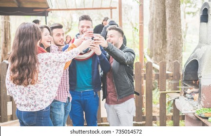 Happy Friends Cheering At Barbecue Dinner Outdoor - Young People Drinking Red Wine For Bbq In Garden Backyard - Friendship And Party Concept - Focus On Glasses - Warm Vivid Filter