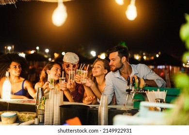 Happy friends cheering and drinking cocktails at beach party outdoor - Soft focus on right man face - Shutterstock ID 2149922931