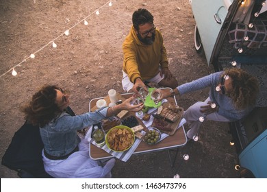 Happy friends cheering and drinking wine during camping vacation at the beach with vintage van. People having fun at weekend summer evening with camper. Youth lifestyle togetherness and party concept - Powered by Shutterstock