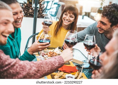 Happy Friends Cheering Red Wine Glasses Sitting At Bar Restaurant Table - Group Of Young People Having Dinner Party Outdoors - Food And Beverage Lifestyle Concept With Guys And Girls Hanging Out