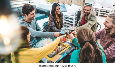 Happy Friends Cheering Red Wine Glasses Sitting At Bar Restaurant Table - Group Of Young People Having Dinner Party Outdoors - Food And Beverage Lifestyle Concept With Guys And Girls Hanging Out