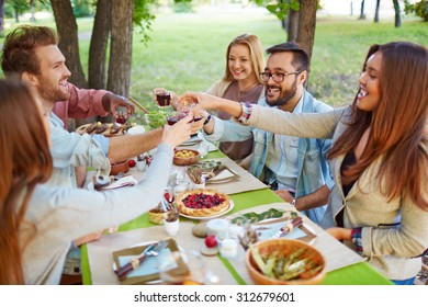 Happy Friends Cheering Up At Thanksgiving Party Outdoors