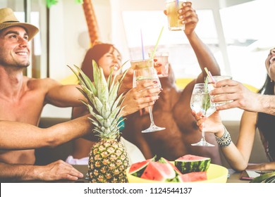 Happy friends cheering with tropical cocktails in patio boat party - Young people having fun in summer vacation - Youth lifestyle, friendship and holiday concept - Main focus on left woman hand - Powered by Shutterstock