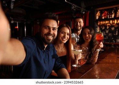 Happy friends with cocktails taking selfie together in bar - Powered by Shutterstock