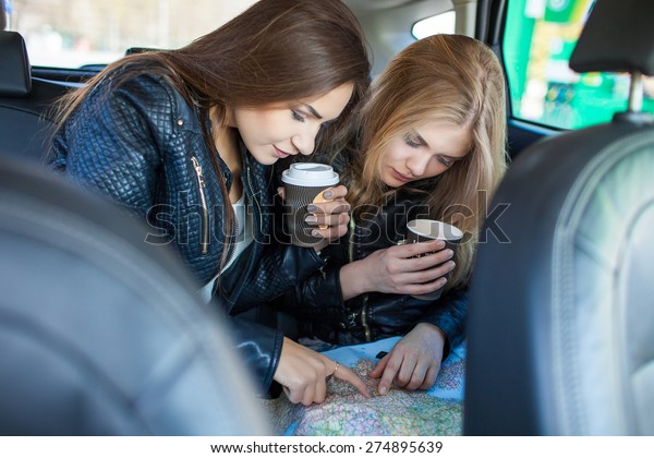 Happy friends with cup of coffee in car. Holiday\
trip of friends