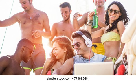 Happy friends dancing and drinking beers at boat dj set party - Young people having fun in exclusive tropical sea tour - Youth lifestyle, travel and summer vacation concept - Focus on disc jockey face