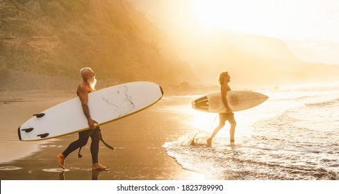 Happy friends with different age surfing together on tropical ocean - Sporty people having fun during vacation surf day - Elderly and youth people sport lifestyle concept - Powered by Shutterstock