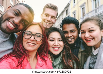 Happy friends from diverse cultures and races taking selfie with back lighting - Youth and friendship concept with young people having fun together - Main focus on left two guys - Retro filter - Shutterstock ID 691180921