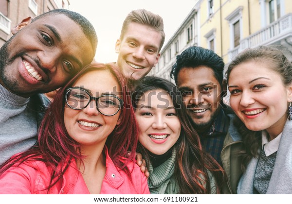 Happy friends from diverse cultures and races\
taking selfie with back lighting - Youth and friendship concept\
with young people having fun together - Main focus on left two guys\
- Retro filter