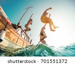 Happy friends diving from sailing boat into the sea - Young people jumping inside ocean in summer excursion day - Vacation, youth and fun concept - Soft focus on left man - Fisheye lens distortion