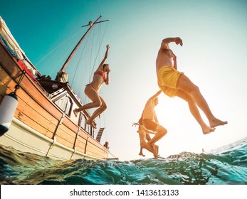 Happy Friends Diving From Sailing Boat Into The Sea - Young People Jumping Inside Ocean In Summer Excursion Day - Vacation, Youth And Fun Concept - Main Focus On Close-up Man - Fisheye Lens Distortion