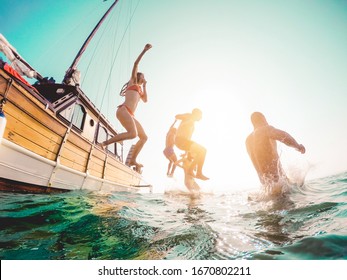 Happy friends diving from sailing boat into the sea - Young people jumping inside ocean in summer excursion day - Vacation, youth and fun concept - Main focus on close-up man - Fisheye lens distortion