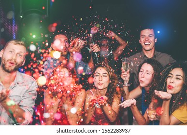 Happy friends doing party throwing confetti in nightclub - Group young people having fun celebrating new year holidays together in disco club - Youth culture entertainment lifestyle concept