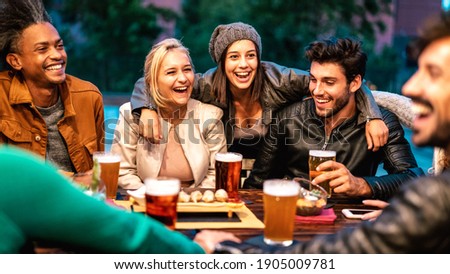 Happy friends drinking beer at brewery bar dehor - Friendship lifestyle concept with young milenial people enjoying time together at open air pub - Warm color tones on vivid filter with focus on girls