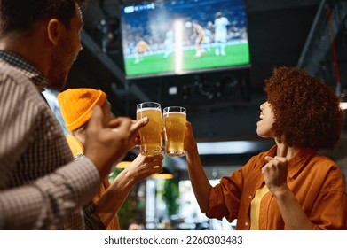 Happy friends drinking beer and cheering together in sports bar - Powered by Shutterstock