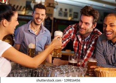 Happy friends drinking beer at counter in pub, chatting with female bartender, smiling. - Powered by Shutterstock