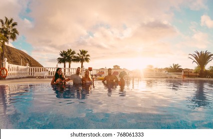 Happy Friends Drinking Champagne In Pool Party At Sunset - Rich People Having Fun In Exclusive Tropical Vacation - Holiday And Friendship Concept - Main Focus On Left Guys - Original Sun Colors Tones