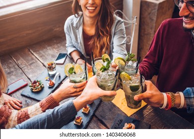 Happy friends drinking mojito at bar restaurant. Concept about young people having fun 