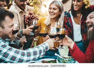 Happy friends drinking red wine at farm house vineyard countryside - Group of young people enjoying lunch break together outside - Hands holding wineglasses at sunset golden hour  - Powered by Shutterstock