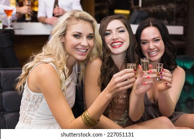 Happy friends drinking shots together at the bar