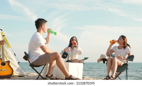 Happy friends with drinks in camp and laughing together in holidays on sand beach near camping tent vacation time at sunset, Young Asian group woman and man in summer travel outdoor - Powered by Shutterstock