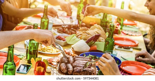 Happy Friends Eating Barbecue Meat Outdoor In City Park On Summer Time - Young People Having Fun Drinking Bear At Bbq Party - Friendship And Food Concept - Focus On Sausages - Warm Contrast Filter