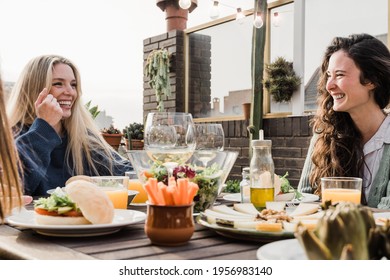 Happy Friends Eating Vegan Food With Wine Outdoors In Summer Sunset At Patio Restaurant - Main Focus Right Woman Face