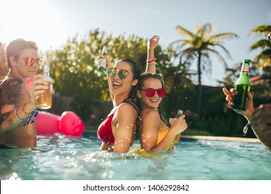 Happy Friends Enjoying In Swimming Pool Party. Young People In Swimming Pool, Drinking, Having Fun And Enjoying Holiday.