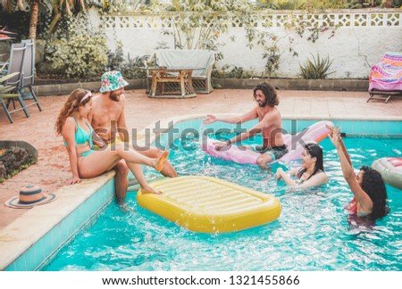 Happy friends floating with air lilo ball at swimming pool party - Young people having fun on summer holidays vacation - Travel, friendship, youth and tropical concept - Focus on center guys faces