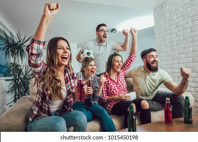 Happy friends or football fans watching soccer on tv and celebrating victory at home.Friendship, sports and entertainment concept. - Shutterstock ID 1015450198