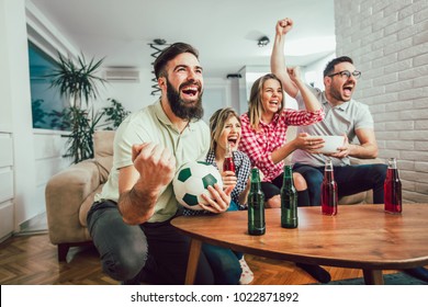 Happy Friends Or Football Fans Watching Soccer On Tv And Celebrating Victory At Home.Friendship, Sports And Entertainment Concept.