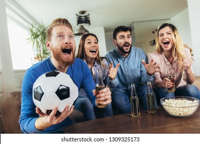 Happy friends or football fans watching soccer on tv and celebrating victory at home.Friendship, sports and entertainment concept. - Shutterstock ID 1309325173