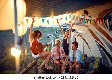 Happy friends in front of camper rv cheering with drinks have party.