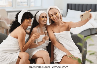 Happy friends with glasses of sparkling wine taking selfie indoors. Spa party - Powered by Shutterstock