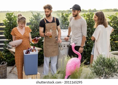 Happy Friends Hang Out On A Picnic, Grilling Food And Standing With Alcohol Drinks At Backyard On Nature. Small Group Of People Cooking And Spending Summertime Outdoors