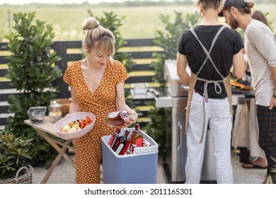 Happy Friends Hang Out On A Picnic, Grilling Food And Standing With Alcohol Drinks At Backyard On Nature. Small Group Of People Cooking And Spending Summertime Outdoors