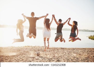 Fröhliche Freunde haben Spaß am Strand - Junge Leute spielen im Freien im Sommerurlaub.