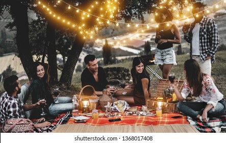 Happy Friends Having Fun At Bbq Dinner With Vintage Lights Outdoor Drinking Wine - Young People Celebrating On Weekend Summer Night - Friendship, Party And Youth Concept - Focus On Center Couple